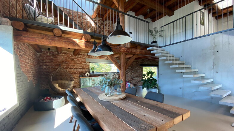 Der Wohnbereich schließt sich unmittelbar an. Die selbst gebaute Treppe führt in die oberen Etagen. Auch Tisch und Lampen sind aus wiederverwendeten Materialien. Der Korbsessel in der Ecke ist ein Lieblingsplatz.