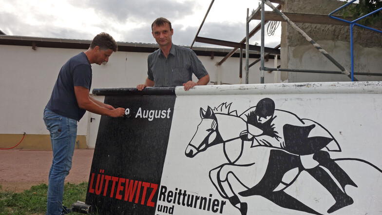 Olaf Planitz (rechts) und Roger Schulz vom Vorstand des Reitvereins Lüttewitz erneuern für das Reitturnier am kommenden Wochenende die Aufschrift auf einem Aufsteller. Im Hintergrund ist der Anbau zu sehen, der ein neues Dach bekommt.
