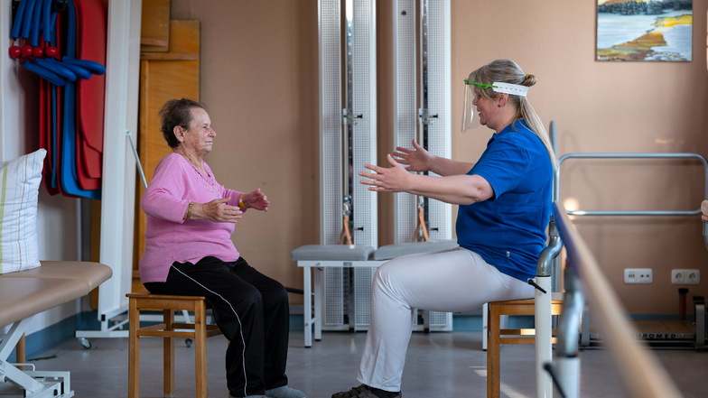Physiotherapeutin Silvana Mohr von der Fachklinik für Geriatrie in Radeburg motiviert Gisela Druschke, ihren Brustkorb noch etwas mehr zu dehnen. Die 82-jährige Patientin hat eine Corona-Infektion