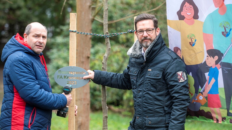 Schönfelds Bürgermeister Falk  Lindenau (l.) und Kronospan-Geschäftsführer David Brenner (r.) kennzeichneten auf einem Schild die Baumspende des Unternehmens für die Gemeinde.
