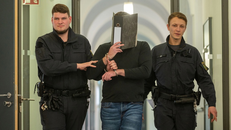 Eduard T. ist in Dresden wegen versuchten Totschlags angeklagt. Auf dem Weg zum Prozess hielt er sich am Mittwoch einen Ordner vors Gesicht.