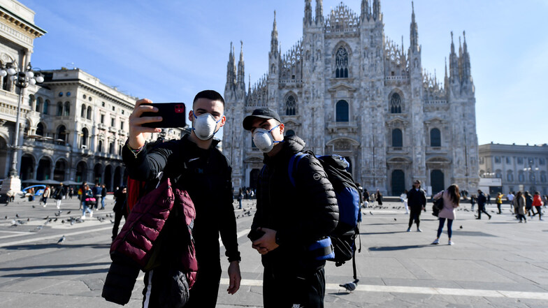 Touristen fotografieren sich mit Mundschutz vor der Kathedrale in Mailand. 