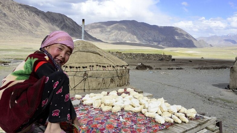 Ein Hirtenmädchen trocknet inmitten der Berge des Pamirgebirges den Käse für ihre Familie.
