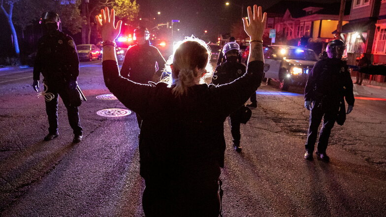 USA, Oakland: Ein Demonstrant steht vor Polizisten und hält dabei beide Arme nach oben bei einem Protest gegen Polizeigewalt in den USA.