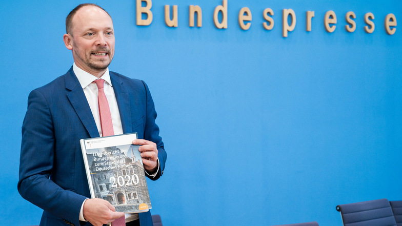 Marco Wanderwitz (CDU), Ostbeauftragter der Bundesregierung, zeigt den Jahresbericht zum Stand der Deutschen Einheit 2020. Auf dem Titel ist die Peterstraße 7 in Görlitz zu sehen.