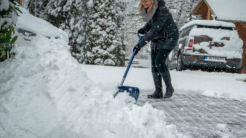 Wintereinbruch in der Region Döbeln: Am Sonntag waren die ersten Schneehaufen am Straßenrand zu sehen. Susann Posselt aus Steina schiebt ihre Einfahrt frei.