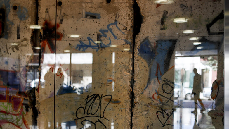 Argentinien, Buenos Aires: Ein Mann wird in einem Glas reflektiert, das ein Segment der Berliner Mauer schützt. 