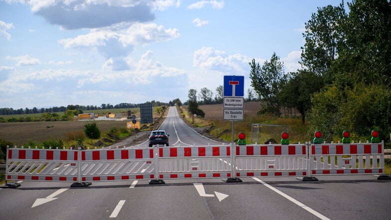 Ein Baustellenfahrzeug fährt über eine gesperrte Straße zu einer Zufahrt zum Baugelände der Intel-Chipfabrik auf dem "Eulenberg".