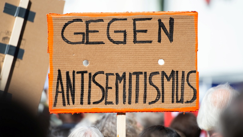 Ein Person hält bei einer Kundgebung eines Bündnisses gegen Antisemitismus ein Plakat mit der Aufschrift "Gegen Antisemitismus" in die Höhe.
