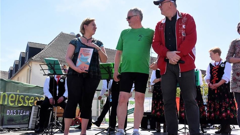 Dorit Binner, Mitarbeiterin der Geschäftsführung des Querxenlandes in Seifhennersdorf,  übernimmt von Landrat Bernd Lange den Staffelstab für die 18. Sternradfahrt. Michael Kutter  moderiert die Staffelstabübergabe.