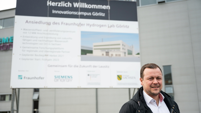 Fraunhofer-Aufbauleiter Sebastian Schmidt vor der Bautafel für das Wasserstoff-Testlabor im Innovationscampus Görlitz.