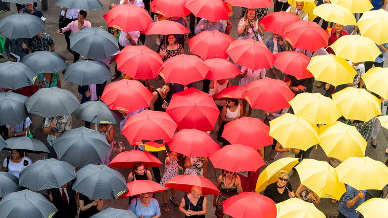 Eingebürgerte Menschen stehen im Jahr 2019 mit schwarz-rot-goldenen Regenschirmen nach dem Einbürgerungsfest vor dem Sächsischen Landtag.