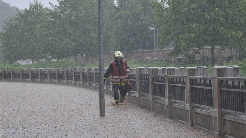 Ein Feuerwehrmann kämpft sich durch das überflutete Triebischtal in Meißen. Starkregen hatte hier einen Erdrutsch ausgelöst.