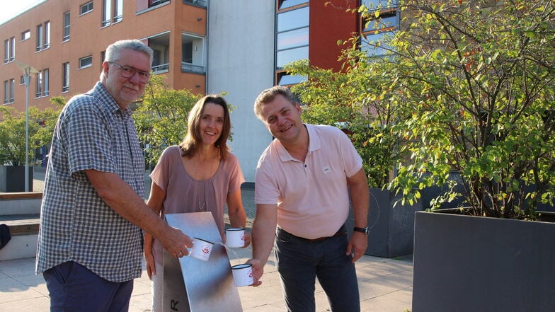 Oberbürgermeister Thomas Schubert, Bürgermeisterin Friederike Trommer sowie Jörg Morgenstern von der WAB Coswig mbH testen den neuen Trinkwasserbrunnen am Lovosicer Platz.