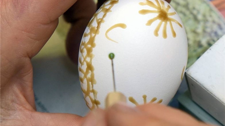 Muster gestalten Die Stecknadelkuppe oder ein anderes Hilfsmittel in das flüssige Wachs tauchen und damit das Muster vorsichtig auf das Ei auftragen.