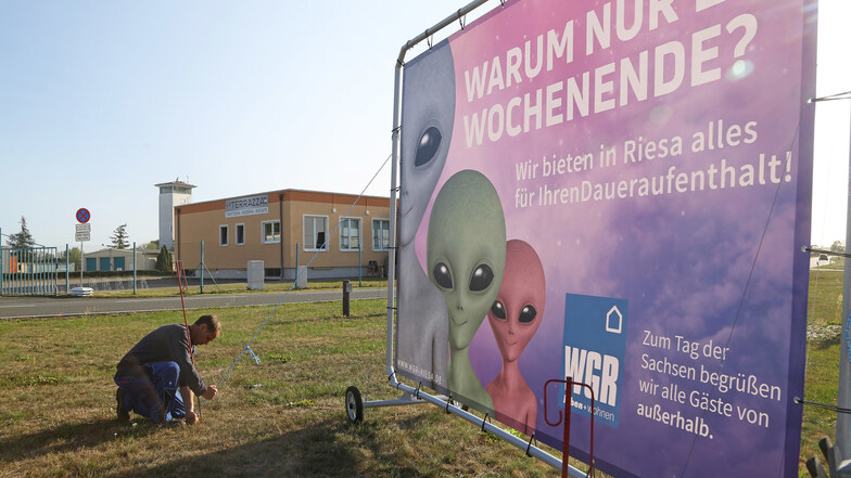 Michael Löwe von der Firma RDL installiert ein Plakat auf dem Großparkplatz am Flugplatz Göhlis. Die anderen Parkplätze sind in Groptitz und Röderau-Süd.