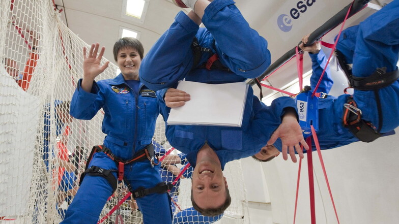 Astronautin Samantha Cristoferetti (l) und Astronaut Matthias Maurer (M) winken während eines Parabelflugs.