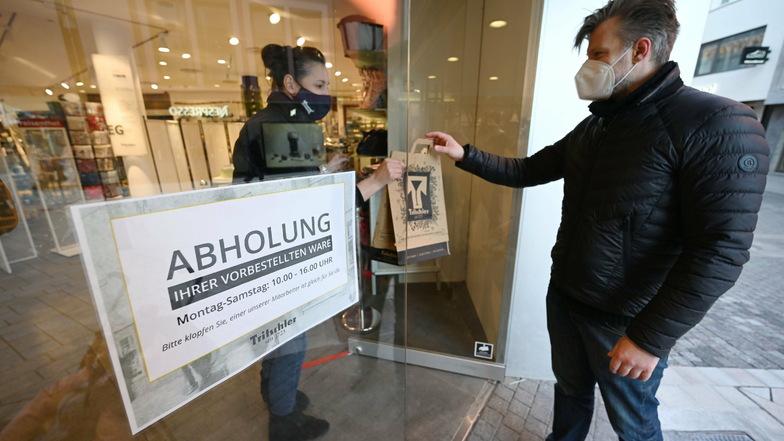 Eine Verkäuferin übergibt im Eingang eines Haushaltswarengeschäfts in Stuttgart einem Kunden bestellte Ware. In Sachsen ist das nicht möglich.