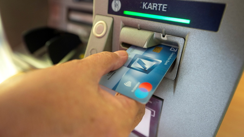 Eine Passantin hebt mit Ihrer EC-Karte an einem Geldautomaten in Großenhain Bargeld ab. Der Trend geht aber in eine ganz andere Richtung.