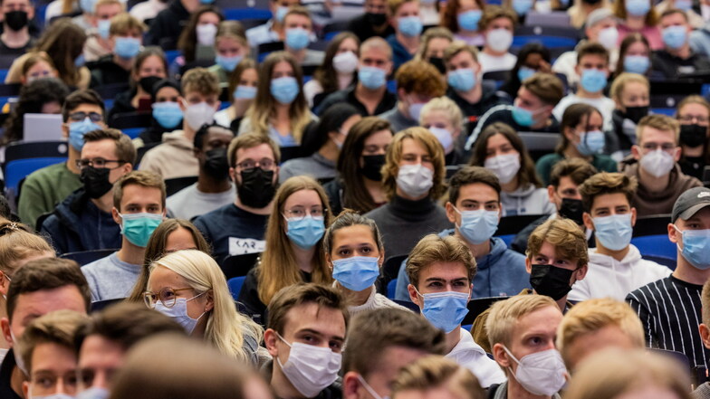 Studierende tragen Maske, während sie dicht nebeneinander bei der Vorlesung sitzen. An den Universitäten haben das erste Mal seit Beginn der Corona-Pandemie die Vorlesungen im Wintersemester 2021/22 in Präsenz unter 3G-Bedingungen begonnen.