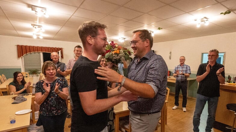 Falk Hentschel (rechts) wird von Alexander Cardaun (links) mit einem Blumenstrauß beglückwünscht. Hentschel bleibt Bürgermeister.