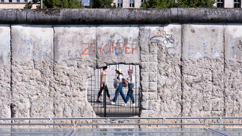 Passanten sind durch ein Loch in einem verbliebenen  Stück der Berliner Mauer zu sehen. Diese Mauer hat immerhin 28 Jahre gehalten. Wie lange hält die Mauer zur AfD?
