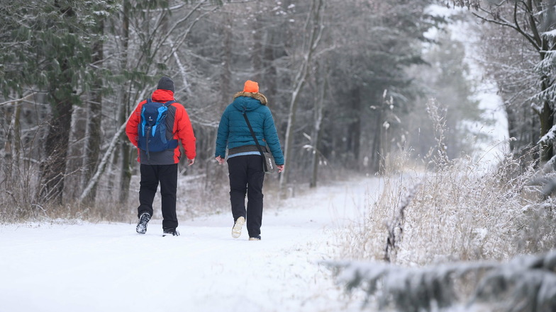 Spaziergänger gehen am Wochenende in Altenberg auf einem verschneiten Wanderweg entlang.
