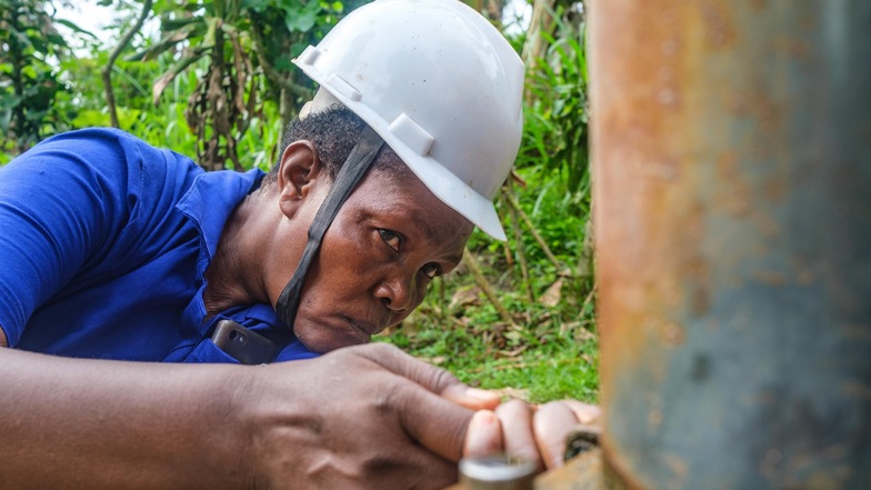Margaret Nakafu ist als Handpumpenmechanikerin im Dorf Katutu im Einsatz, um die Wasserversorgung sicherzustellen. Im Bild ist zu sehen, wie sie gerade eine Wasserpumpe der Gemeinde repariert.