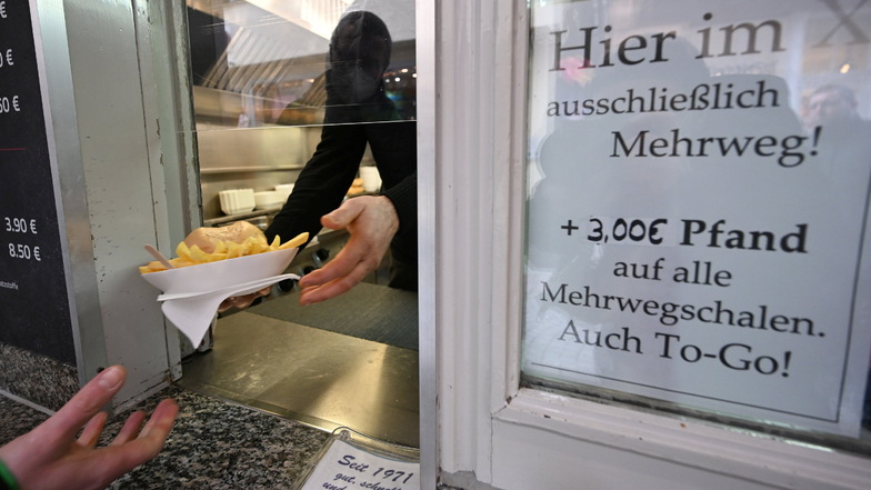 ARCHIV - 28.01.2021, Baden-Württemberg, Tübingen: Eine Hand hält an einem Imbiss einen Mehrwegteller mit Pommes und einem Burger.