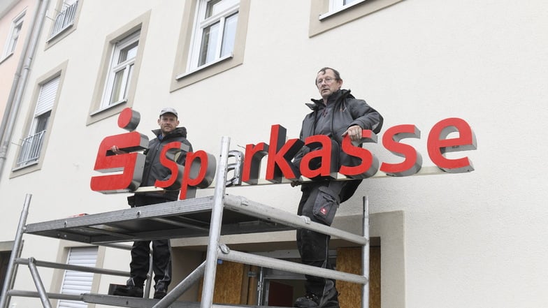 Der Schriftzug Sparkasse kehrte bereits am Montag zurück. Robert Scheuermann (li.) und Carsten Fleischer von Firma Werbeplan Dresden haben ihn angebracht.