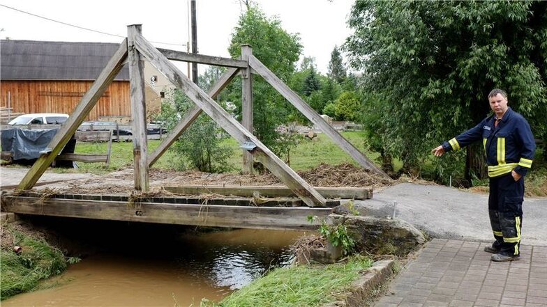 Eine Brücke in Ziegenhain wurde vom Wasser um einen halben Meter verrückt, wie Ortswehrleiter Thiel zeigt.