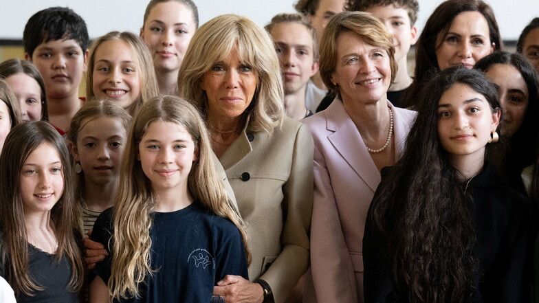 Brigitte Macron und Elke Büdenbender stehen im Romain-Rolland-Gymnasium zwischen Schülerinnen und Schülern.