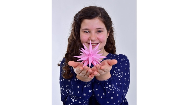 Sternekind Lucy präsentiert den neuen rosafarbenen Kunststoffstern mit 13 Zentimeter Durchmesser.