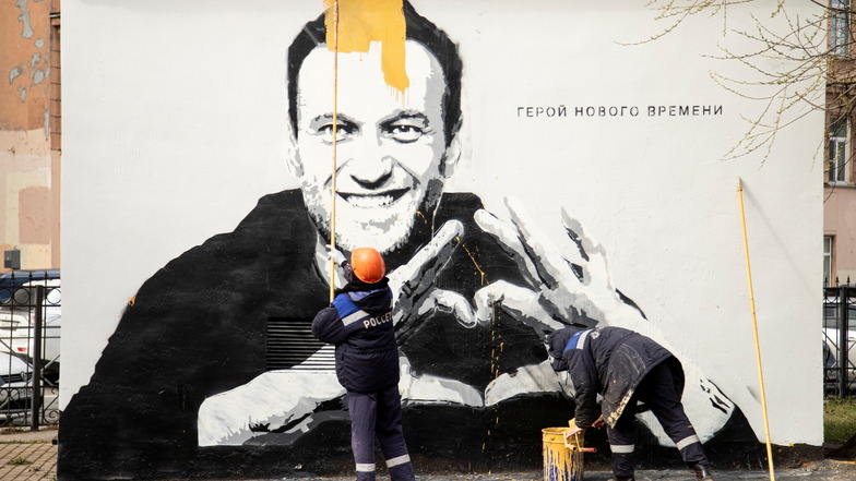 In St. Petersburg übermalen städtische Arbeiter ein Graffiti mit dem Konterfei des inhaftierten russischen Oppositionsführers Nawalny.