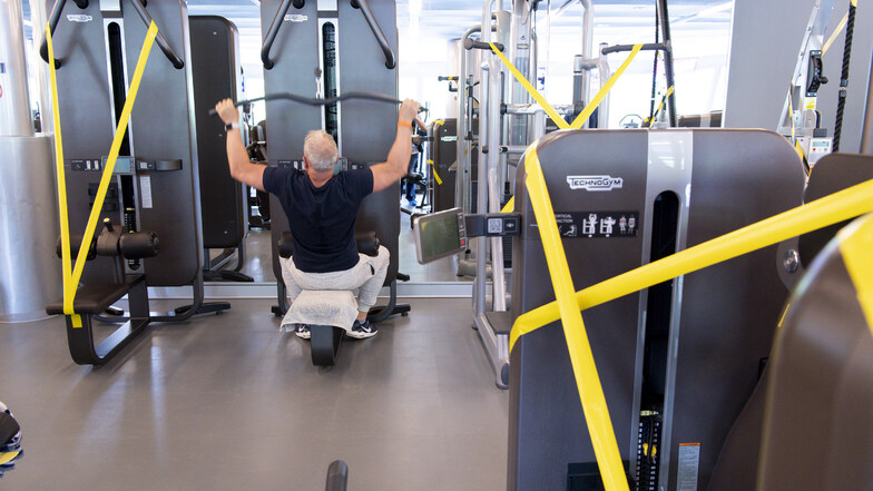 Allein im Fitnessstudio: Ein Mann trainiert zwischen abgesperrten Geräten.