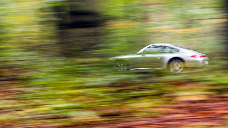 Ein Porsche fährt durch den herbstlich verfärbten Wald