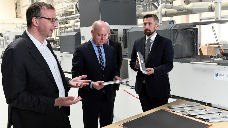 Geschäftsführer Holger Gritzka (von links) erklärt dem Landtagsabgeordneten Henning Homann und dem sächsischen Wirtschaftsminister Martin Dulig den Aufbau der neuen gedruckten Batteriezellen. Im Hintergrund steht die erste Beschichtungsanlage für die