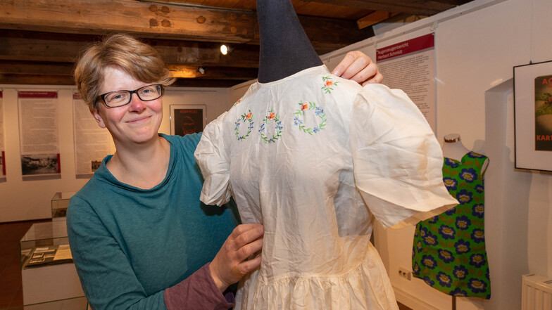 Museumsleiterin Ulrike Hentzschel zeigt ein Kleid aus Fallschirmseide.