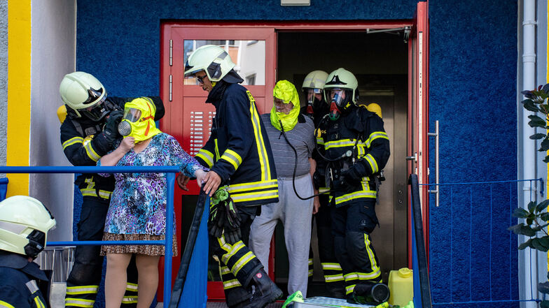 Feuerwehrleute holten die Menschen mit Masken aus dem Haus, die vor den giftigen Dämpfen schützen.
