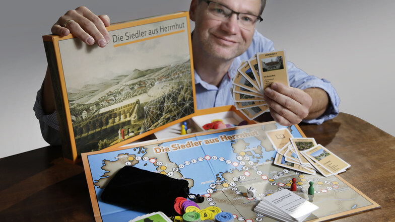 Lars-Arne Dannenberg zeigt das Herrnhuter Brettspiel, das kostenfrei bestellt werden kann.