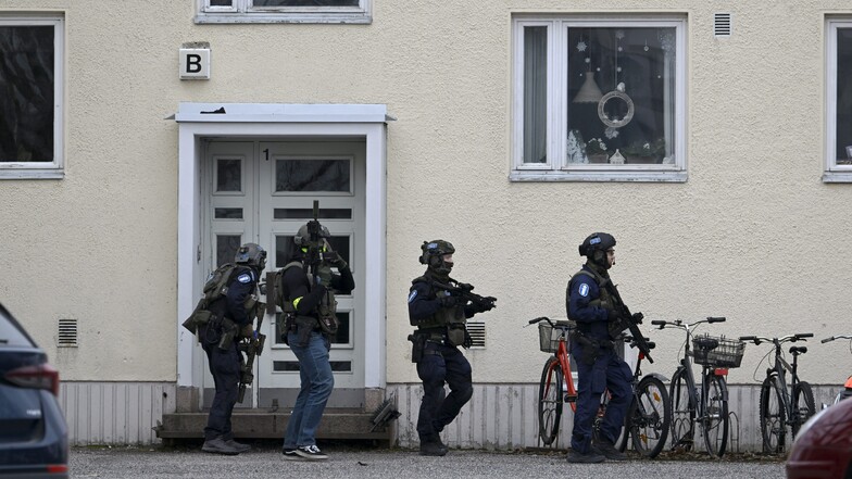 Bewaffnete Polizisten gehen an einer Tür der Viertola-Schule vorbei.