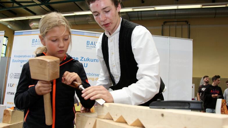 Ludwig Henke aus Naundorf ist Zimmererlehrling. Beim Tag der Ausbildung zeigt er Emilio, wie man mit einem Stemmeisen Holz bearbeitet.