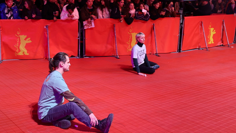 Zwei junge Menschen haben sich auf dem roten Teppich festgeklebt während der Eröffnung der Berlinale.