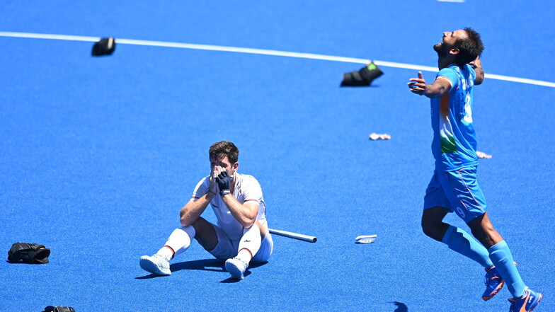 Gurjant Sing aus Indien jubelt nach dem Gewinn der Bronzemedaille. Lukas Windfeder sitzt enttäuscht daneben auf dem Boden.