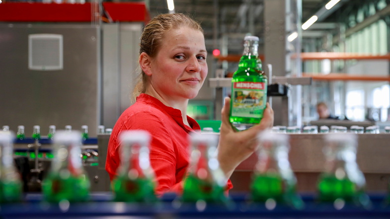 Prokuristin Lucie Kunath präsentiert die erste am neuen Produktionsstandort in Großschönau abgefüllte Flasche Menschel-Limo: Waldmeister.