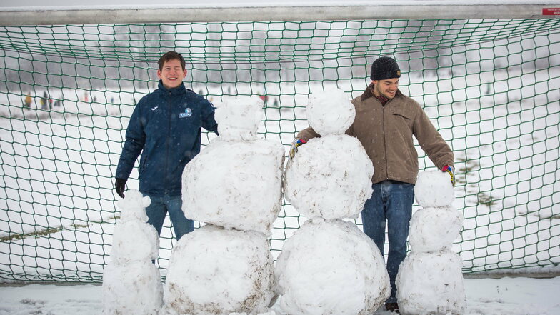 Es schneit in Dresden. Ben (mit Mütze) und Ansgar bauen an den Johannstädter Elbwiesen eine Schneemannfamilie.
