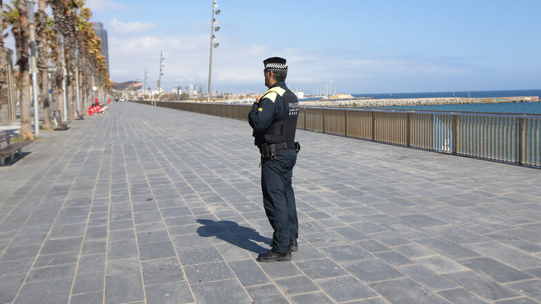 Ein Polizist bewacht in Barcelona den Zugang zum Strand. Zur wirksameren Bekämpfung des Coronavirus müssen die Spanier bis mindestens 11. April zu Hause bleiben.