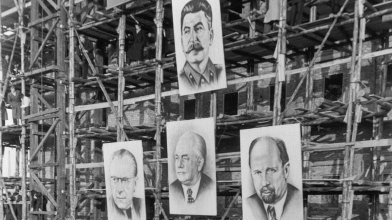 Ein symbolkräftiges Bild aus dem Jahr 1952: Am Gerüst eines Baus an der Berliner Stalin-Allee hängt der sowjetische Diktator dominierend über seinen Vasallen Otto Grotewohl, Wilhelm Pieck und Walter Ulbricht.