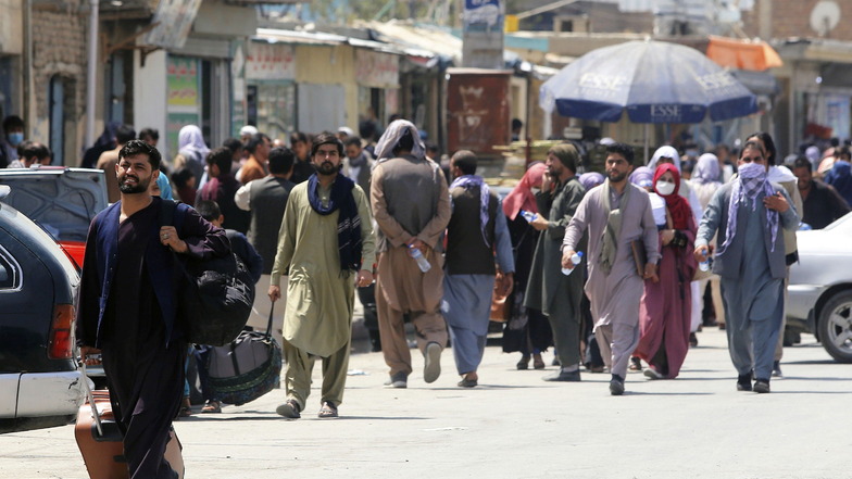 Menschen begeben sich zu einer Militäreinrichtung auf einem Flughafen in Kabul.