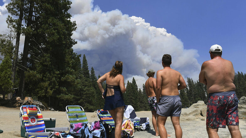 Eine Familie beobachtet vom Ufer des Shaver Lake aus den aufsteigenden Rauch eines Waldbrandes.